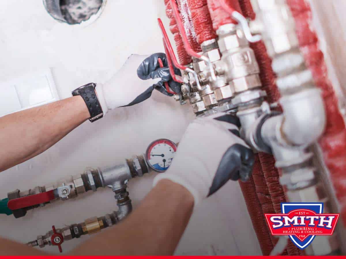 Technician adjusting pipes and valves, illustrating a plumbing remodel in progress